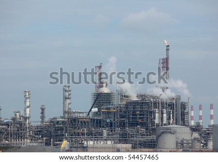 View of working oil refinery plant with  curling air emission smoke.