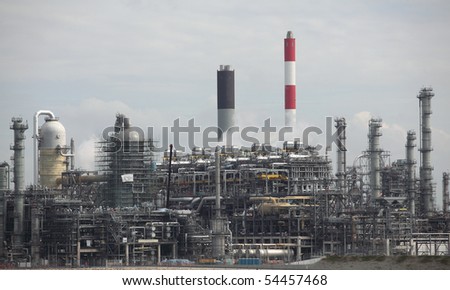Oil refinery plant with it\'s stainless steel cylinders, it\'s valves, chimneys, pipes, tubes and construction and visible air-emission.