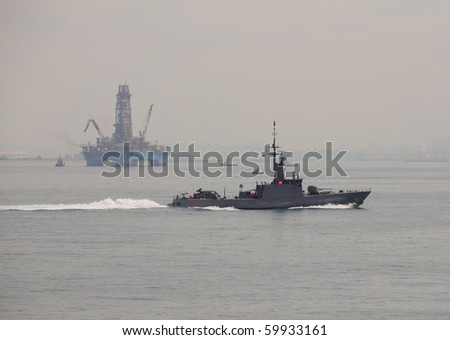 Naval ship patrolling area of oil drilling rig