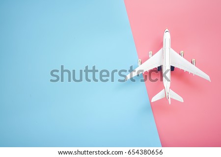 Flat lay design of travel concept with plane on blue and pink background with copy space.