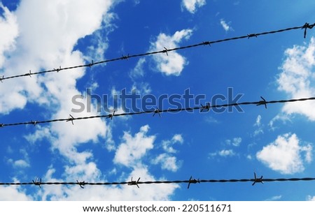 barbed wire fence with white clouds and blue sky background