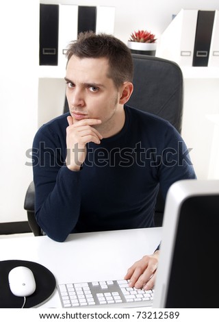 Young man thinking in front of his computer in the office ambient