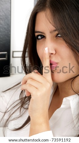 A beautiful brunette business woman saying shh it\'s a secret.