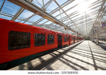 Sun is shining trough the transparent roof of metro station with subway train