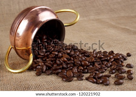 Fallen copper cup and lot of coffee beans
