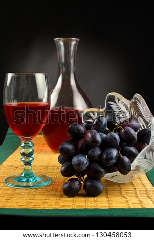 Grapes with glass of red wine and carafe on place mat