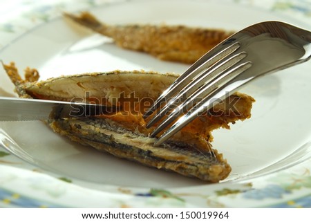 Cleaning cooked fish (fried european vendace, small freshwater whitefish) for eating with fork and knife