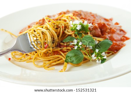 Spaghetti with meat sauce on plate with fork and oregano leaves with flowers