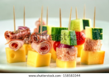 Different cocktail stick snacks , with cheese , zucchini , meat jelly , cucumber and cold cuts rolls