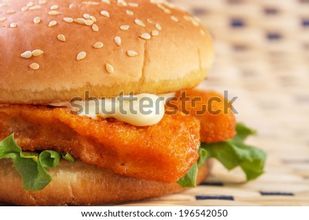 Fish stick burger with mayonnaise on table mat closeup