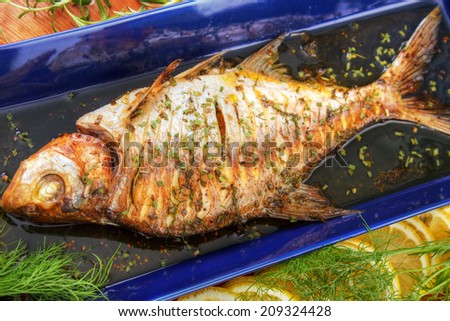 Oven cooked fish with herbs on blue fish platter