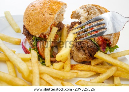 Eating fries and burger with fork