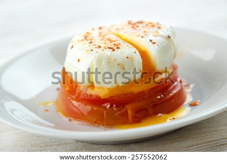Poached egg above cooked tomato slices on dish