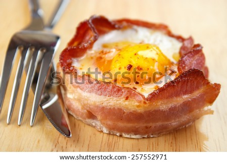 Oven cooked bacon wrapped egg with fork and knife
