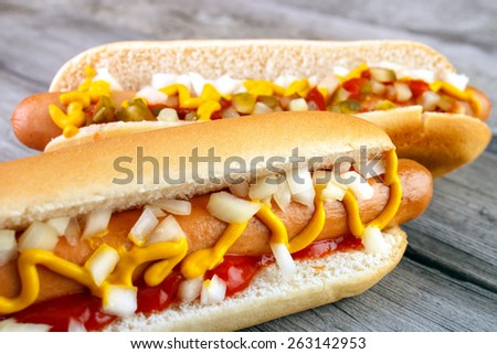 Two hot dogs with ketchup  closeup  , yellow mustard and onion on gray wooden surface