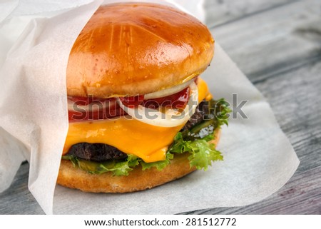 Homemade packed food , cheeseburger wrapped in paper on grey wooden surface