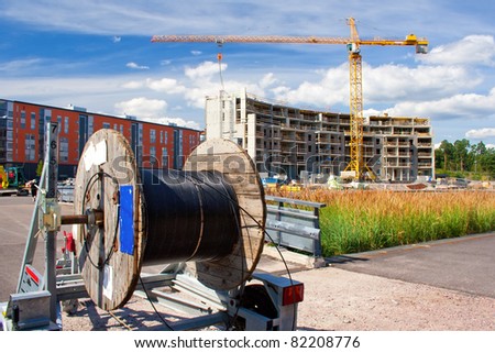 A reel of heavy coaxial cable used for cable-TV underground construction, and the construction site in the background
