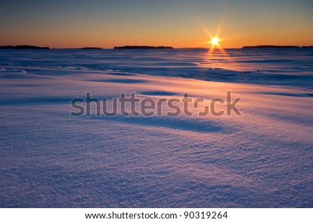 Sunrise over snow covered beach and sea