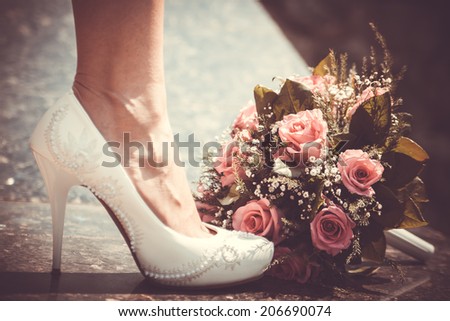 White shoe of the Bride next to wedding bouquet. Vintage wedding theme background