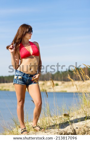 Girl in denim shorts posing on the beach in summer sunny day