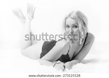 Black and white Soft Focus Photo of beautiful blonde girl lying on the carpet in black underwear
