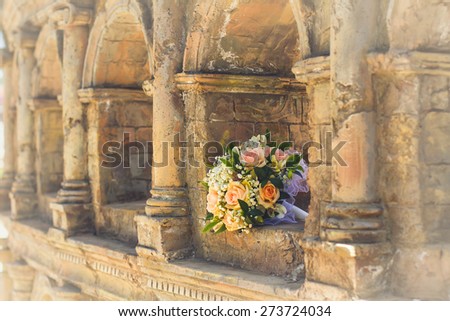 wedding bridal bouquet with white, peach and orange roses lies in the ancient building. Wedding theme