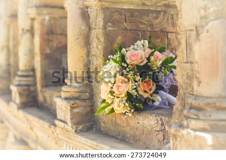 wedding bridal bouquet with white, peach and orange roses lies in the ancient building. Wedding theme