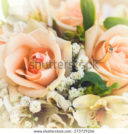 golden rings on wedding bridal bouquet with white, peach and orange roses. Wedding theme
