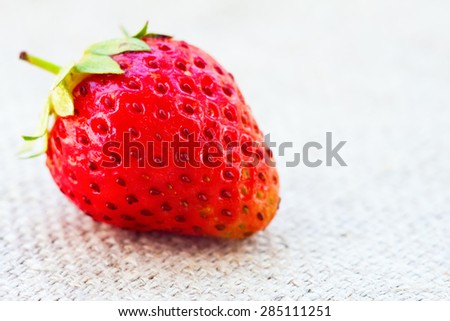 Fresh organic strawberry on a fabric texture. Macro photo
