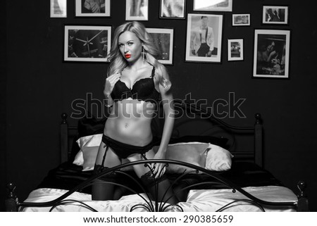 glamour picture of sexy blonde woman in black lingerie laying on the bed in classic interior. Black and White photo.