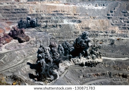 excavators,trucks and heavy machinerys in open cast mine after blast among dust and smoke