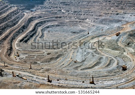 close up of quarry extracting iron ore with heavy trucks, excavators, diggers and locomotives at night