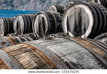 a lot of oak wine casks with madeira wine while maderization on solarium with mountain and sea on background