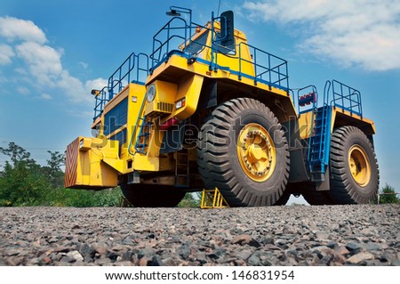 A picture of a big yellow mining truck at work site on blue sky with white clouds background
