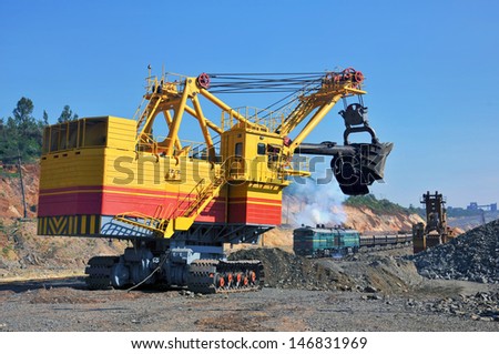 Excavator loading iron ore into goods wagon on the iron ore opencast mine