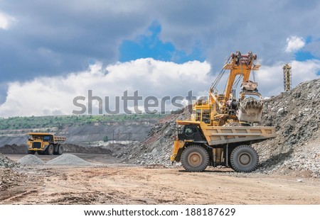 big yellow excavator extracting iron ore in opencast mine and loading heavy truck big yellow excavator extracting iron ore in opencast mine and loading heavy truck