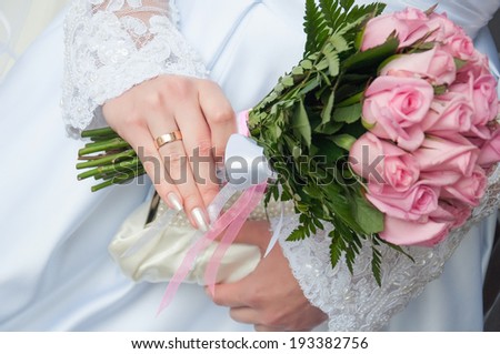 close up of bride hand holding wedding bouquet of roses