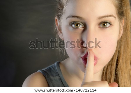 young beautiful woman with finger in its lips saying to him to be kept silent