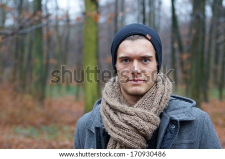 young man with scarf and woolly hat in autumn / winter landscape