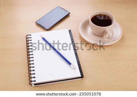 writing pad with pencil, smart phone and cup of coffee on desk