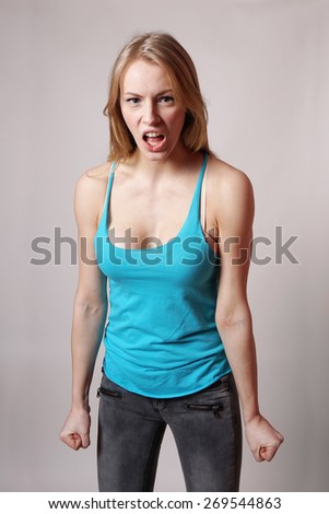 furious angry aggressive young woman screaming with clenched fist
