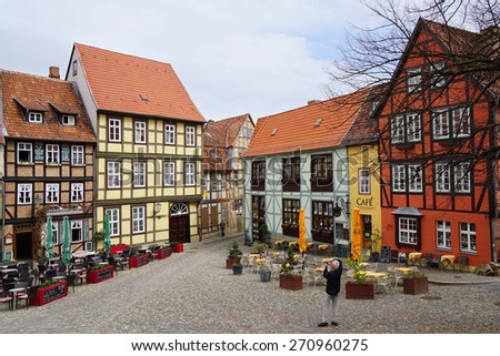 Quedlinburg, Germany - April 16, 2015: Tourist taking photograph of the colorful half-timbered houses on Schlossberg.