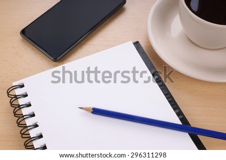 empty writing or note pad with pencil, smart phone and cup of coffee on desk