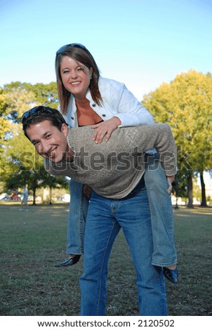 young man carrying attractive girl on his back
