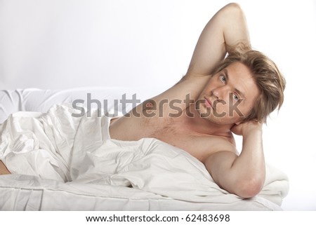 Handsome young model lying in bed naked. Studio shot. See more in my portfolio