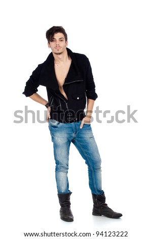 Handsome young fashion model standing and wearing jeans, boots and a black jacket. Isolated on white background. Studio vertical image.
