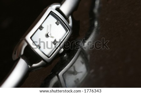 Classic silver watch on a piece of black granite.  Reflection on granite.  Shallow D.O.F