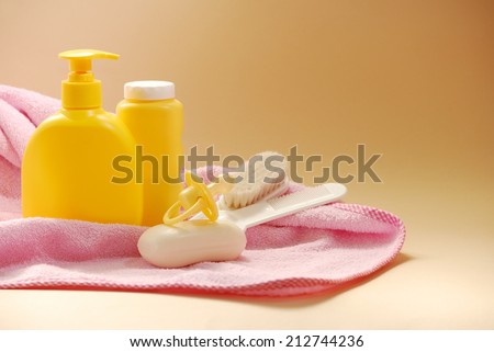 Baby liquid soap, talcum powder, cream and other bathroom accessories on a pink towel