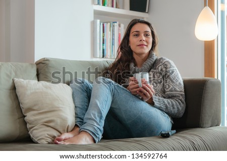Young woman watching tv home in sofa