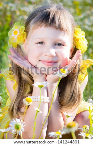 Portrait of a cute little girl in a field of daisies